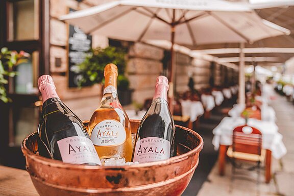 Aussenbereich mit bestuhlter Terrasse und Schirmen